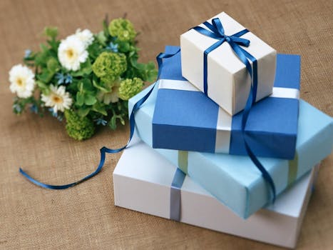 Dary Three beautifully wrapped gift boxes with blue ribbons arranged beside a floral bouquet.